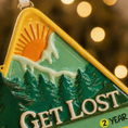 Load image into Gallery viewer, Decorative ornament with a triangle design, sun, trees, and 'GET LOST' text on a blurred light background.
