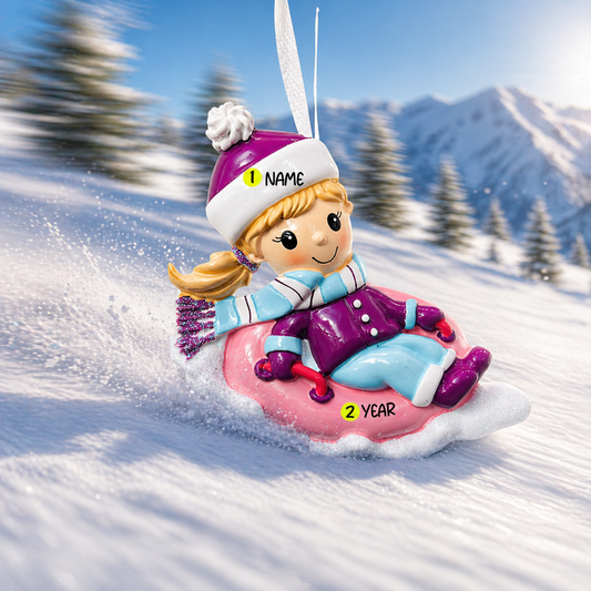 Decorative ornament of a child on an inner tube in the snow with mountains in the background
