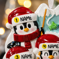 Load image into Gallery viewer, Decorative penguin ornament with customizable name tags against a blurred festive background.
