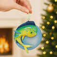 Load image into Gallery viewer, Decorative fish ornament held by a hand with a Christmas tree and fireplace in the background.

