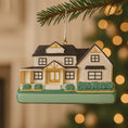 Load image into Gallery viewer, Decorative house ornament hanging on a tree with blurred lights in the background
