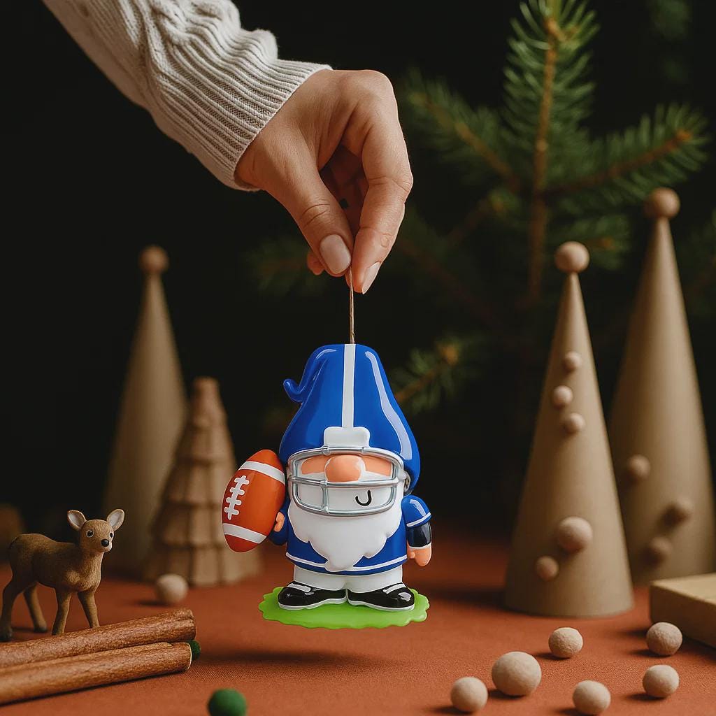 Personalized football gnome Christmas ornament featuring a blue and white gnome character wearing a football helmet and holding a football, customizable name area on the front body and customizable year area on the football, glossy finish with raised 3D front details and flat 2D back, white hanging ribbon, displayed on a snowy football field themed holiday background with pine branches and festive decorations.