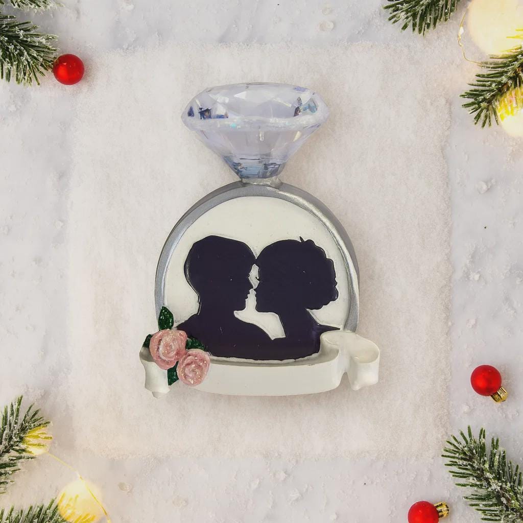 Decorative ornament with silhouettes of a couple and flowers, surrounded by Christmas decorations.