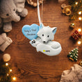 Load image into Gallery viewer, Baby's First Christmas ornament with a blue heart and white fox design on a wooden surface with holiday decorations.
