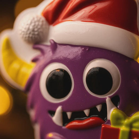 Purple monster toy with a Santa hat and gift, against a blurred background