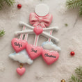 Load image into Gallery viewer, Personalized Baby Girl First Christmas Ornament featuring a dimensional 3D front design with pink glitter bow, heart charms, and hanging cloud detail. The baby’s name is added on the top circle and the year on the cloud, creating a meaningful keepsake. Soft pink tones, layered hearts reading Baby’s First Christmas, and festive holiday accents make it perfect for newborn girl gifts, baby shower presents, and treasured Christmas tree memories.
