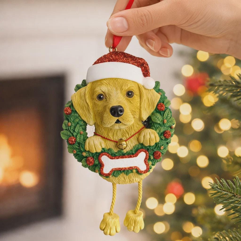 Dog Christmas ornament with a wreath and Santa hat, held by a hand against a festive background.