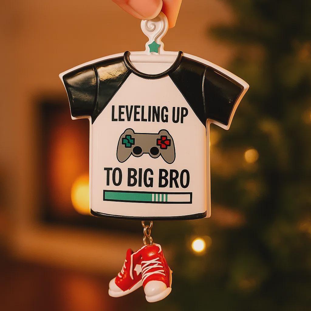 Decorative ornament shaped like a t-shirt with text and gaming controller design, held against a blurred festive background.