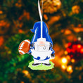 Load image into Gallery viewer, Personalized football gnome Christmas ornament featuring a blue and white gnome character wearing a football helmet and holding a football, customizable name area on the front body and customizable year area on the football, glossy finish with raised 3D front details and flat 2D back, white hanging ribbon, displayed on a snowy football field themed holiday background with pine branches and festive decorations.
