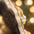Load image into Gallery viewer, Close-up of a decorative item with gold and blue elements against a blurred background
