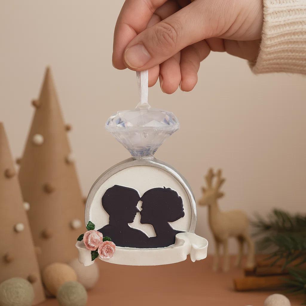 Decorative ornament with a silhouette of a couple and a diamond, held by a hand against a festive background.