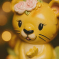 Load image into Gallery viewer, Personalized baby lion Christmas ornament featuring a sweet yellow lion cub wearing a floral crown and holding a small leaf. The bottom banner can be customized with name and year, creating a unique keepsake for a newborn or toddler. Designed in warm yellow and soft pastel tones, this resin baby Christmas ornament is perfect for celebrating Baby’s First Christmas or adding a personalized jungle themed touch to your holiday tree.
