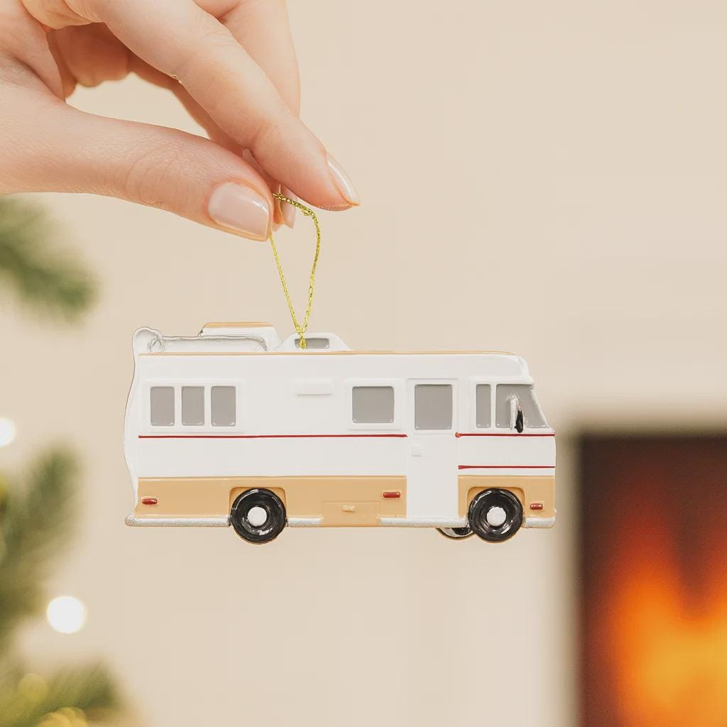 Decorative ornament shaped like a vintage camper van held by a hand against a neutral background.