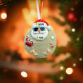Load image into Gallery viewer, Decorative Christmas ornament with a beach-themed Santa Claus design on a blurred Christmas tree background.
