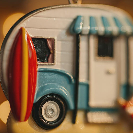 Close-up of a toy camper with a surfboard attached, blurred background