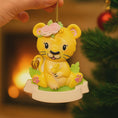 Load image into Gallery viewer, Personalized baby lion Christmas ornament featuring a sweet yellow lion cub wearing a floral crown and holding a small leaf. The bottom banner can be customized with name and year, creating a unique keepsake for a newborn or toddler. Designed in warm yellow and soft pastel tones, this resin baby Christmas ornament is perfect for celebrating Baby’s First Christmas or adding a personalized jungle themed touch to your holiday tree.

