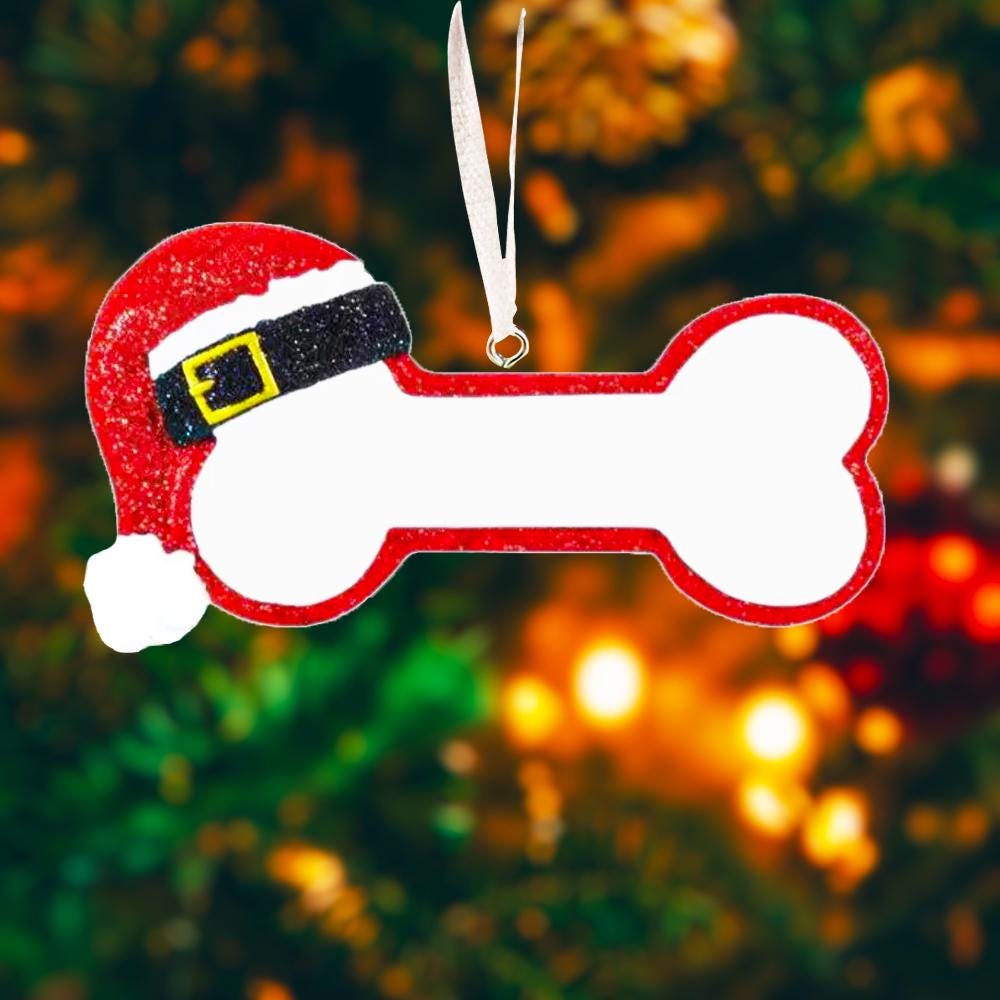 Personalized dog Christmas ornament featuring a bone shaped design with a glitter red Santa hat detail on one end, customizable name area centered on the ornament and customizable year displayed on the opposite side, smooth glossy finish with glitter accents, flat lightweight structure and red hanging ribbon, photographed on a snowy holiday styled background with pine branches, festive Christmas ornaments, dog themed props, and warm seasonal lighting for pet lovers.