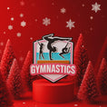 Load image into Gallery viewer, Personalized gymnastics Christmas ornament featuring elegant gymnast silhouette figures in motion, customizable name area on the front banner and customizable year area above the banner, glossy finish with raised 3D front details and flat 2D back, white hanging ribbon, displayed on a soft pink snowy holiday background with festive ornaments greenery and warm Christmas decor.

