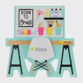 Load image into Gallery viewer, Born to Craft ornament featuring a creative desk scene with colorful craft supplies including scissors paint bottles brushes pencils and storage cups. The ornament showcases a playful crafting workspace design with a modern chair and desk setup. Made from durable resin with a detailed 3D front and flat 2D back for smooth hanging. Includes free handwritten personalization making it a perfect gift for crafters artists DIY lovers and creative kids. Ideal for Christmas trees craft rooms studios and handmade the
