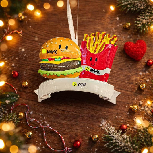 Christmas ornament with a burger and fries on a wooden surface with festive decorations.