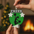 Load image into Gallery viewer, Personalized cheerleading Christmas ornament featuring a bright green glitter background with a cheer silhouette holding pom poms, bold CHEER title at the top, customizable name area on the lower banner, customizable year displayed on a star detail, and additional personalization space for school name or initials, glossy finish with raised 3D front elements and flat 2D back, white hanging ribbon, photographed on a snowy sports field themed holiday background with festive ornaments and winter greenery.
