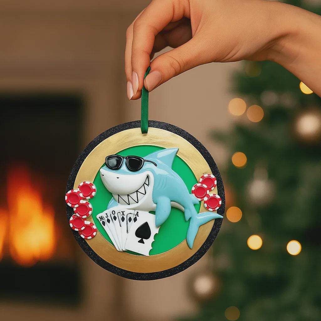 Personalized poker ornament featuring a cool shark character wearing sunglasses with playing cards and red casino chips. Designed in a round ornament style with a glossy finish. Includes free handwritten personalization with one name and year displayed on the front. Shown hanging with a ribbon in a festive holiday setting with greenery snow and seasonal decor. 3D raised front and flat back design perfect for Christmas trees and gifts for poker players casino lovers and card game fans.
