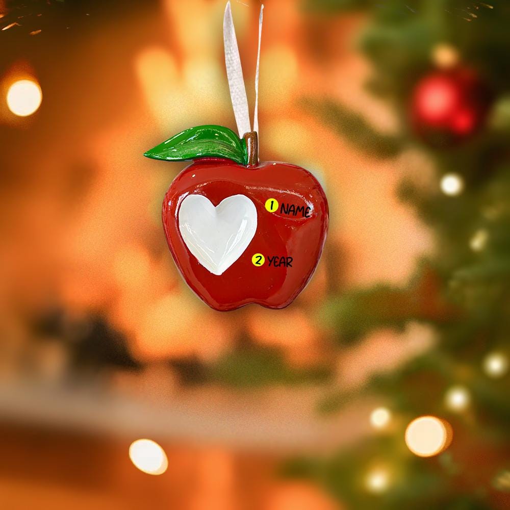 Decorative apple ornament with a heart in the center, hanging on a Christmas tree.
