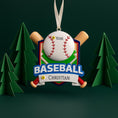 Load image into Gallery viewer, Personalized baseball Christmas ornament featuring a classic baseball and crossed bats design on a shield style background, customizable name area on the front banner and customizable year area on the baseball, glossy finish with raised 3D front details and flat 2D back, white hanging ribbon, displayed on a snowy baseball field themed holiday background with pine branches and festive decorations.
