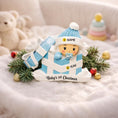 Load image into Gallery viewer, Personalized Baby Boy First Christmas Ornament featuring an adorable baby popping out of a blue gift box with a matching hat and pacifier. The name is displayed on the hat while the year is placed on the ribbon detail, with Baby’s 1st Christmas written along the base. Soft blue and white tones, raised 3D elements, and sweet holiday details make this a charming keepsake. Perfect for newborn boys, baby showers, and celebrating a baby’s very first Christmas season.
