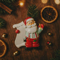 Load image into Gallery viewer, Decorative Santa Claus figurine holding a 'Nice List' sign on a wooden surface with Christmas decorations.
