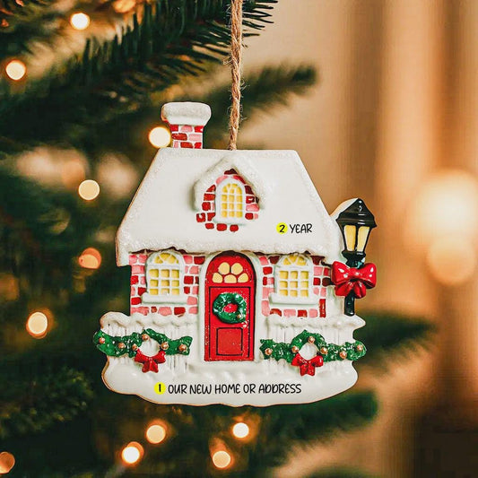 Decorative Christmas house ornament on a tree with lights in the background