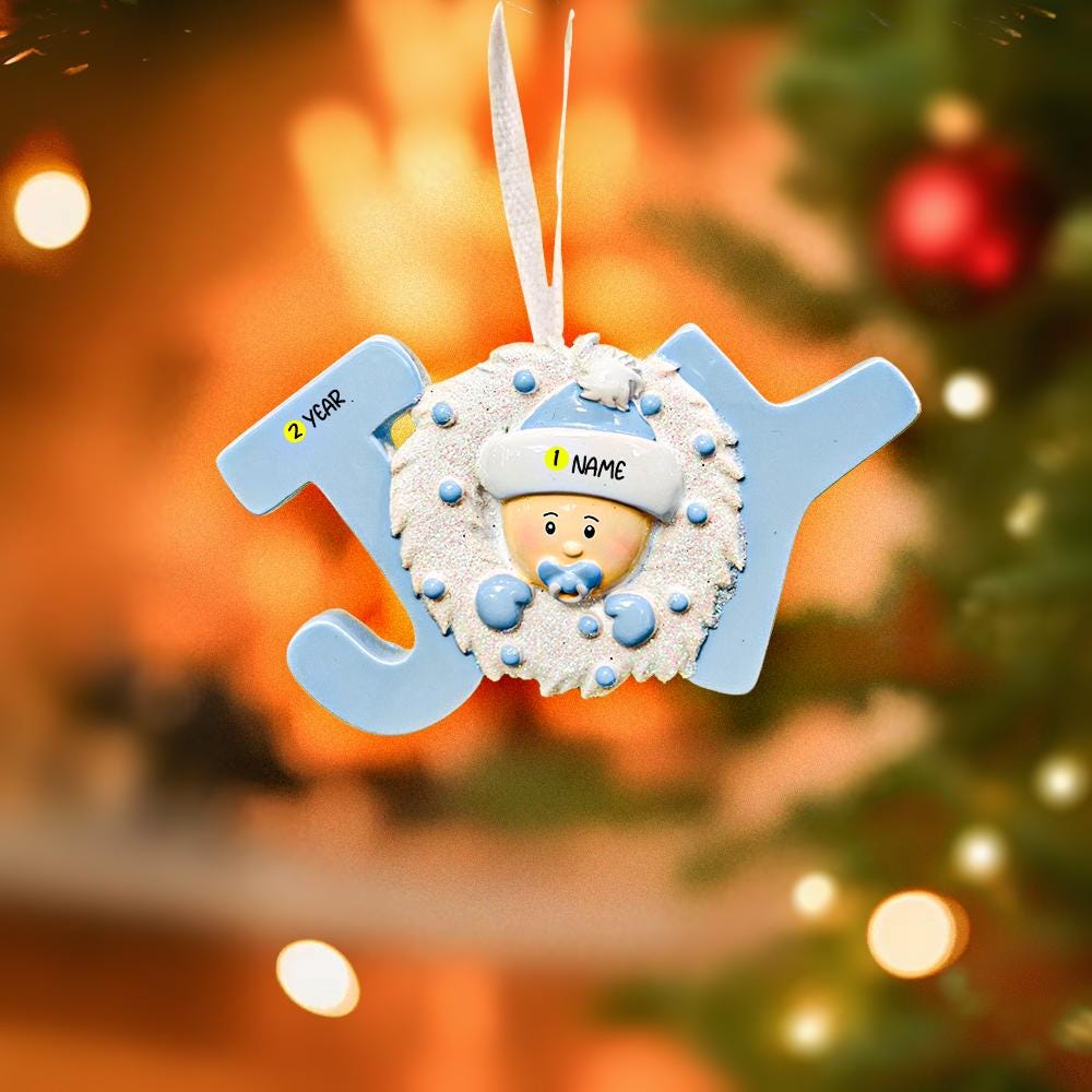 Decorative Christmas ornament with a baby's face and customizable text, hanging against a festive background.