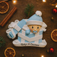 Load image into Gallery viewer, Personalized Baby Boy First Christmas Ornament featuring an adorable baby popping out of a blue gift box with a matching hat and pacifier. The name is displayed on the hat while the year is placed on the ribbon detail, with Baby’s 1st Christmas written along the base. Soft blue and white tones, raised 3D elements, and sweet holiday details make this a charming keepsake. Perfect for newborn boys, baby showers, and celebrating a baby’s very first Christmas season.
