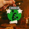 Load image into Gallery viewer, Personalized cheerleading Christmas ornament featuring a bright green glitter background with a cheer silhouette holding pom poms, bold CHEER title at the top, customizable name area on the lower banner, customizable year displayed on a star detail, and additional personalization space for school name or initials, glossy finish with raised 3D front elements and flat 2D back, white hanging ribbon, photographed on a snowy sports field themed holiday background with festive ornaments and winter greenery.

