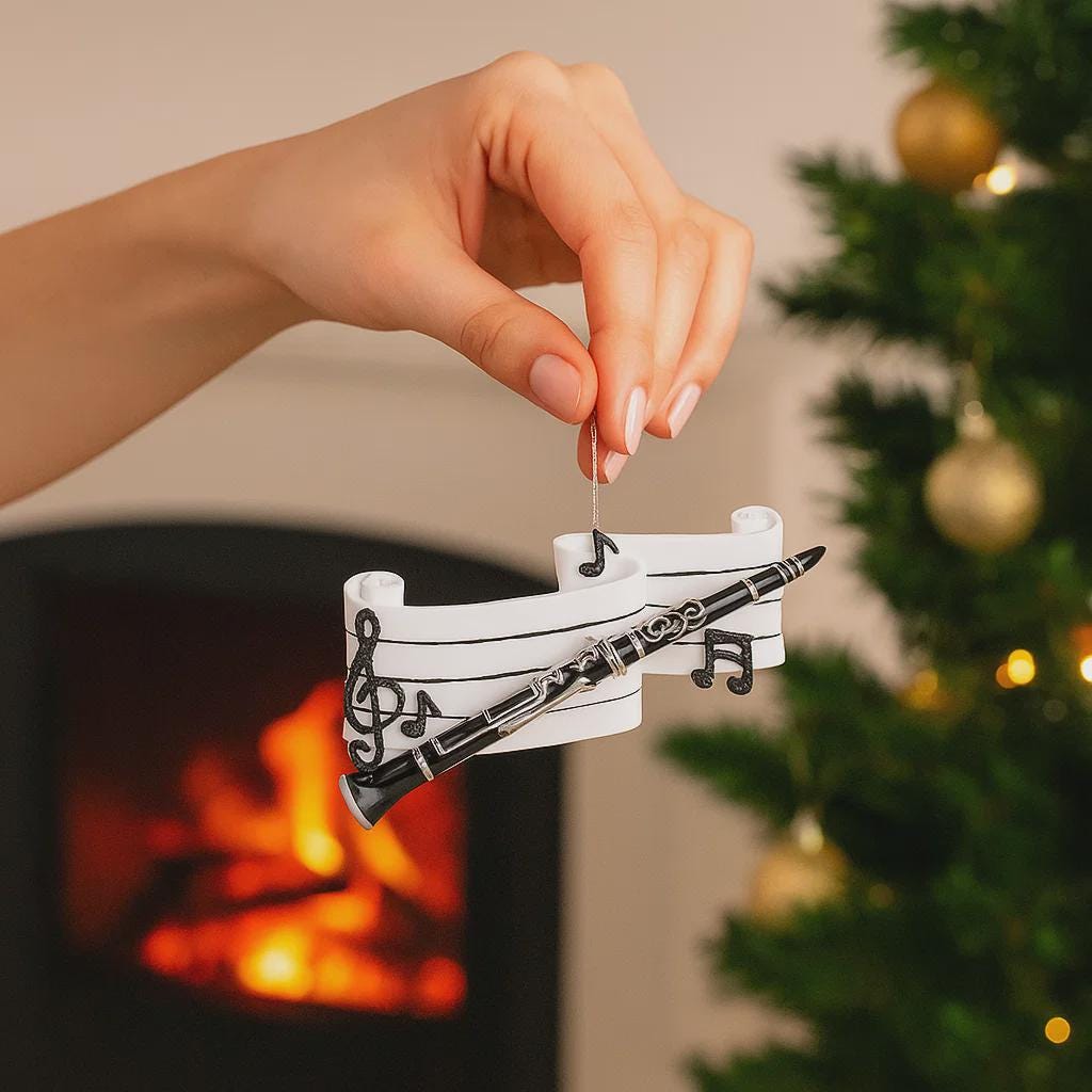 Hand holding a decorative ornament with musical notes in front of a fireplace and Christmas tree.
