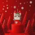 Load image into Gallery viewer, Christmas-themed ornament of a cat in a stocking with red trees and snowflakes on a red background
