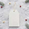 Load image into Gallery viewer, White tag with customizable ornament text on a festive background with Christmas decorations
