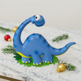 Load image into Gallery viewer, Blue dinosaur figurine on a decorative surface with Christmas ornaments

