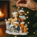 Load image into Gallery viewer, Decorative Christmas ornament with animals wearing winter hats and scarves, held by a hand against a festive background.
