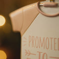 Load image into Gallery viewer, Close-up of a baby outfit with 'Promoted to' text on a blurred background
