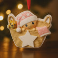 Load image into Gallery viewer, Personalized Baby Girl First Christmas Ornament featuring a detailed 3D front design with a sweet baby resting inside a woven basket, pink nightcap, teddy bear, and hanging star for the year. The baby’s name is added on the hat and the year on the star, creating a meaningful keepsake. Soft pink tones, cozy textures, and dimensional elements make it perfect for newborn girl gifts, baby shower presents, and treasured first Christmas tree memories.
