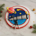 Load image into Gallery viewer, Decorative cake with space-themed design featuring a telescope, planet, and stars on a white surface.

