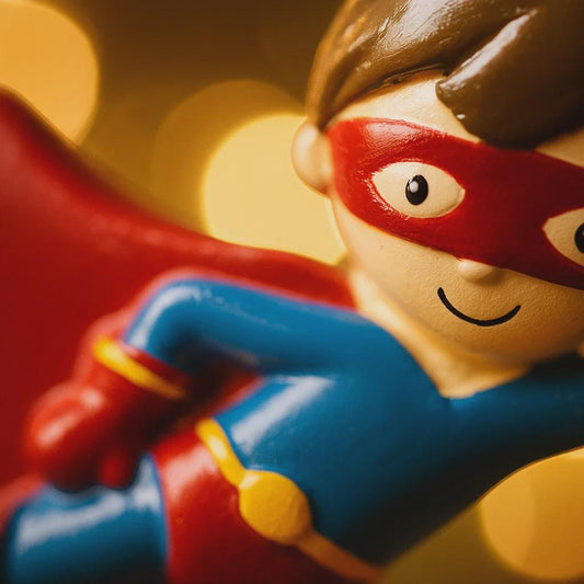 Toy superhero figure with a red mask and cape on a yellow background
