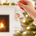Load image into Gallery viewer, Hand holding a angel ornament with a Christmas tree and fireplace in the background
