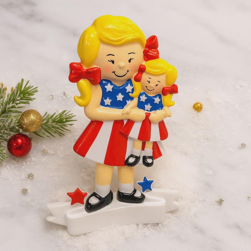 Decorative ornament of a woman holding a child in patriotic outfits on a snowy background.