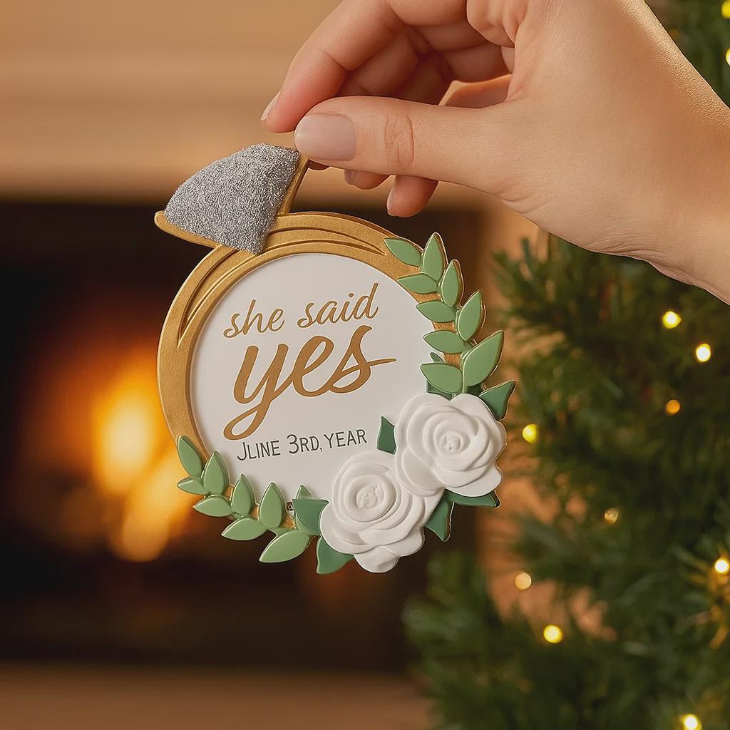 Elegant engagement Christmas ornament featuring gold accents white florals and the phrase she said yes. Personalized with a custom date to commemorate a proposal or engagement moment. A romantic keepsake perfect for celebrating newly engaged couples weddings and meaningful holiday memories.