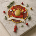 Load image into Gallery viewer, Decorative emblem with firefighter helmet and fire hydrant on a textured surface with Christmas decorations.
