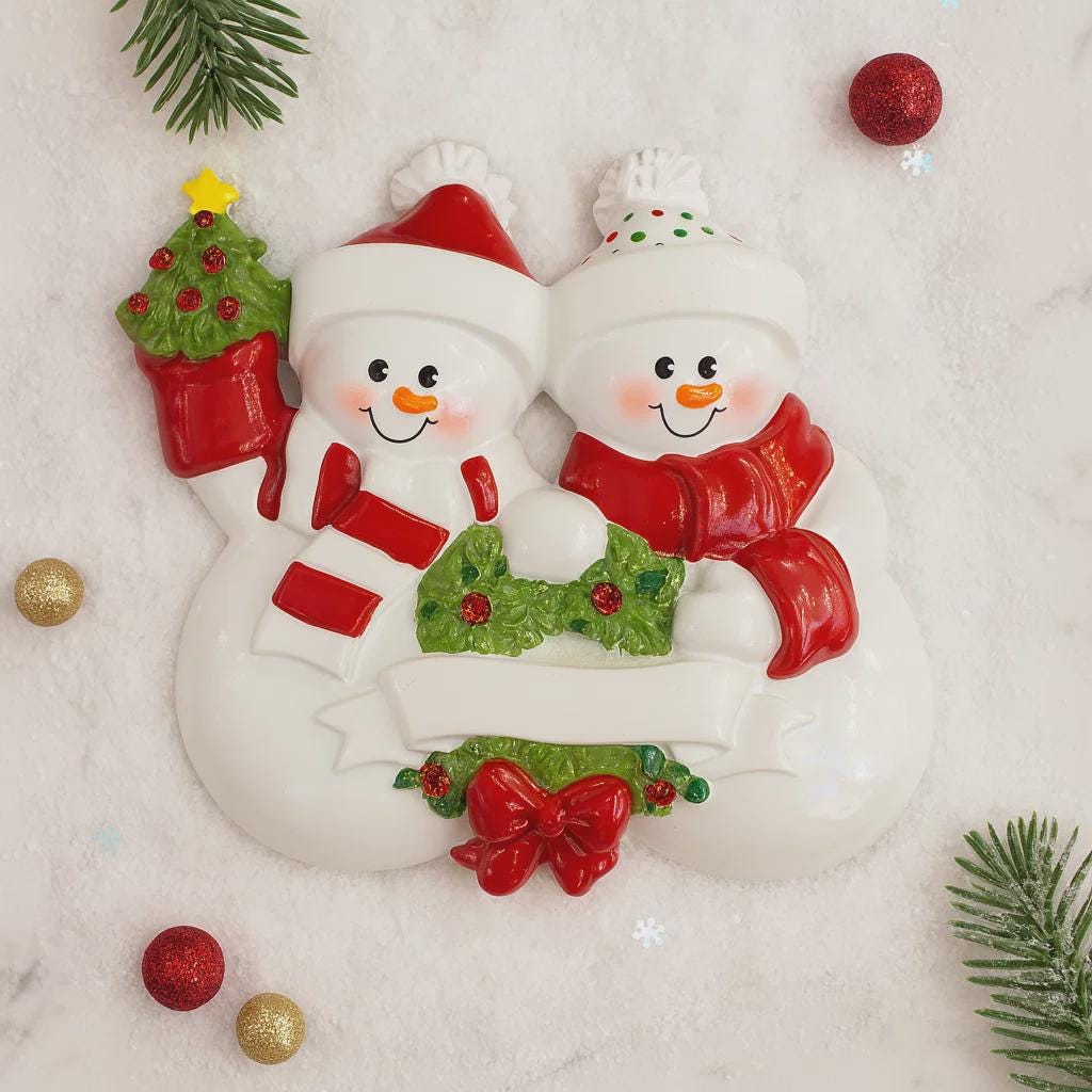 Decorative snowman couple ornament with Christmas decorations on a snowy background