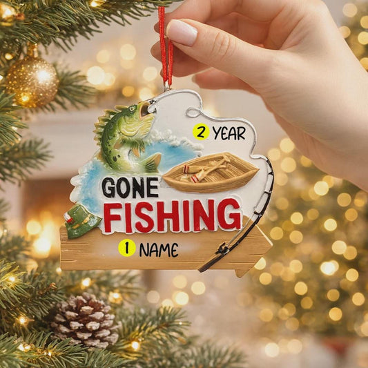 Fishing-themed ornament with a hand holding it against a Christmas tree background.