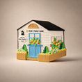 Load image into Gallery viewer, Model of a small house with decorative elements on a beige background
